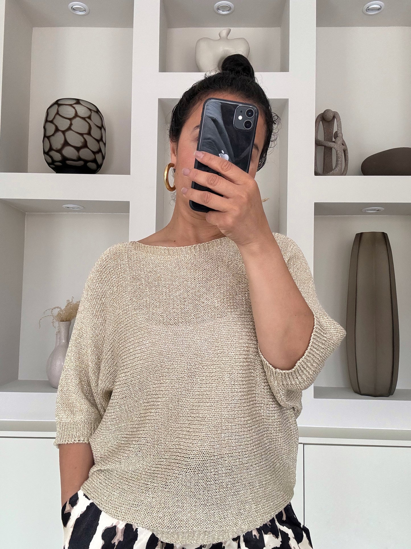 Model draagt de Nora shimmer knit met vleermuismouw en metallic glans in goudzand kleur – VYNAH