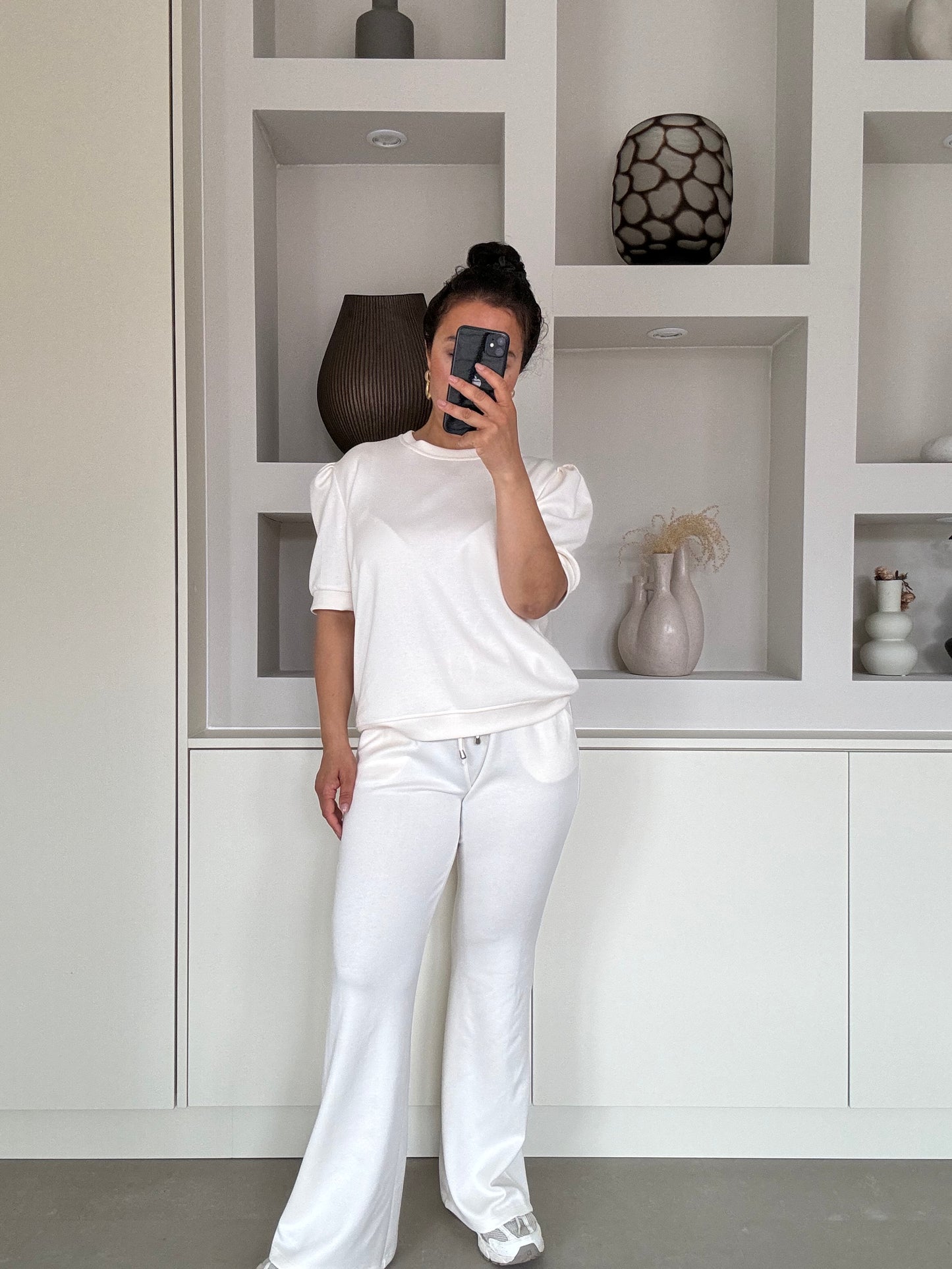 Model draagt de Naya soft set in off white met pofmouw top en flared broek – VYNAH

