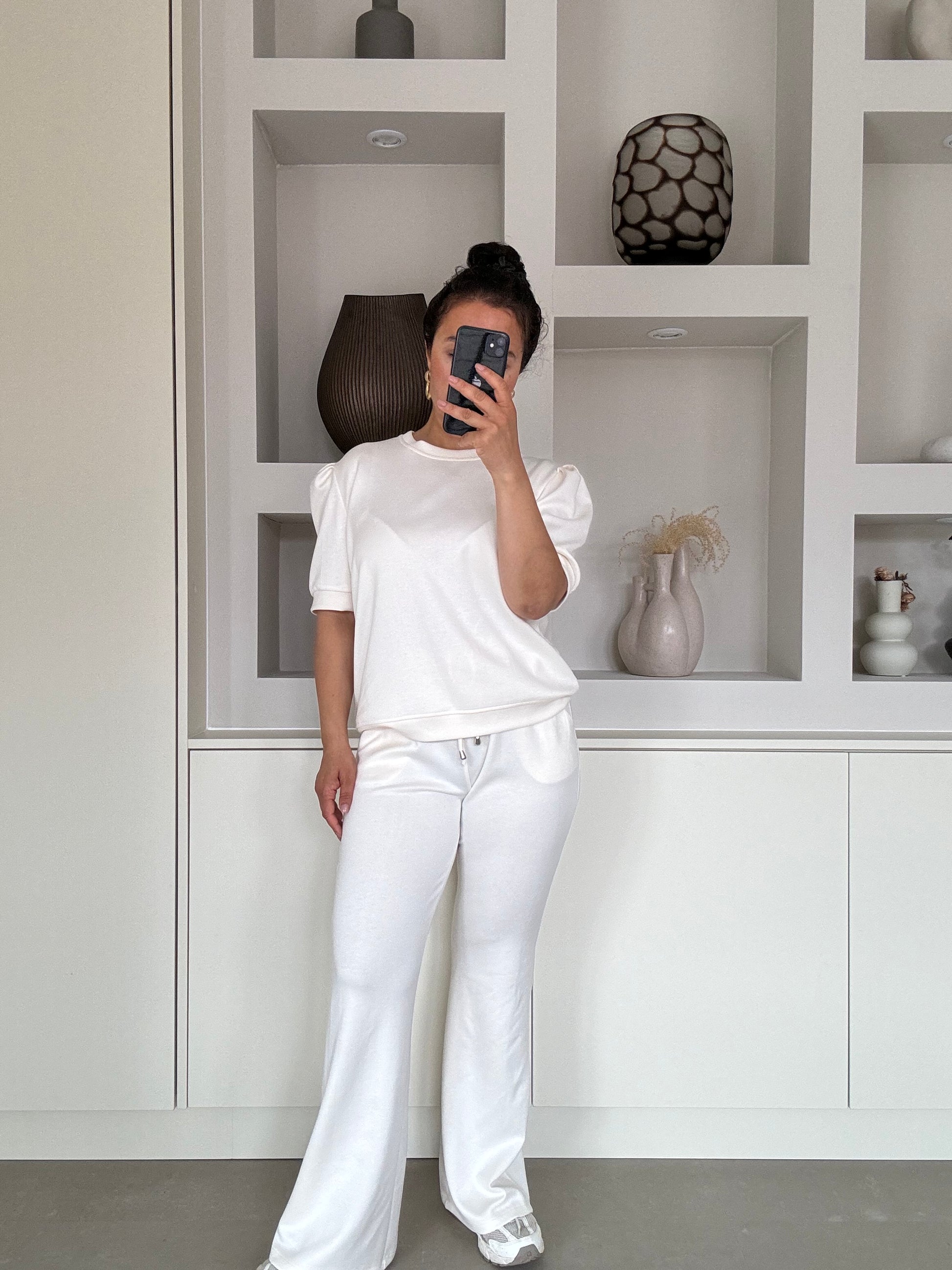 Model draagt de Naya soft set in off white met pofmouw top en flared broek – VYNAH


