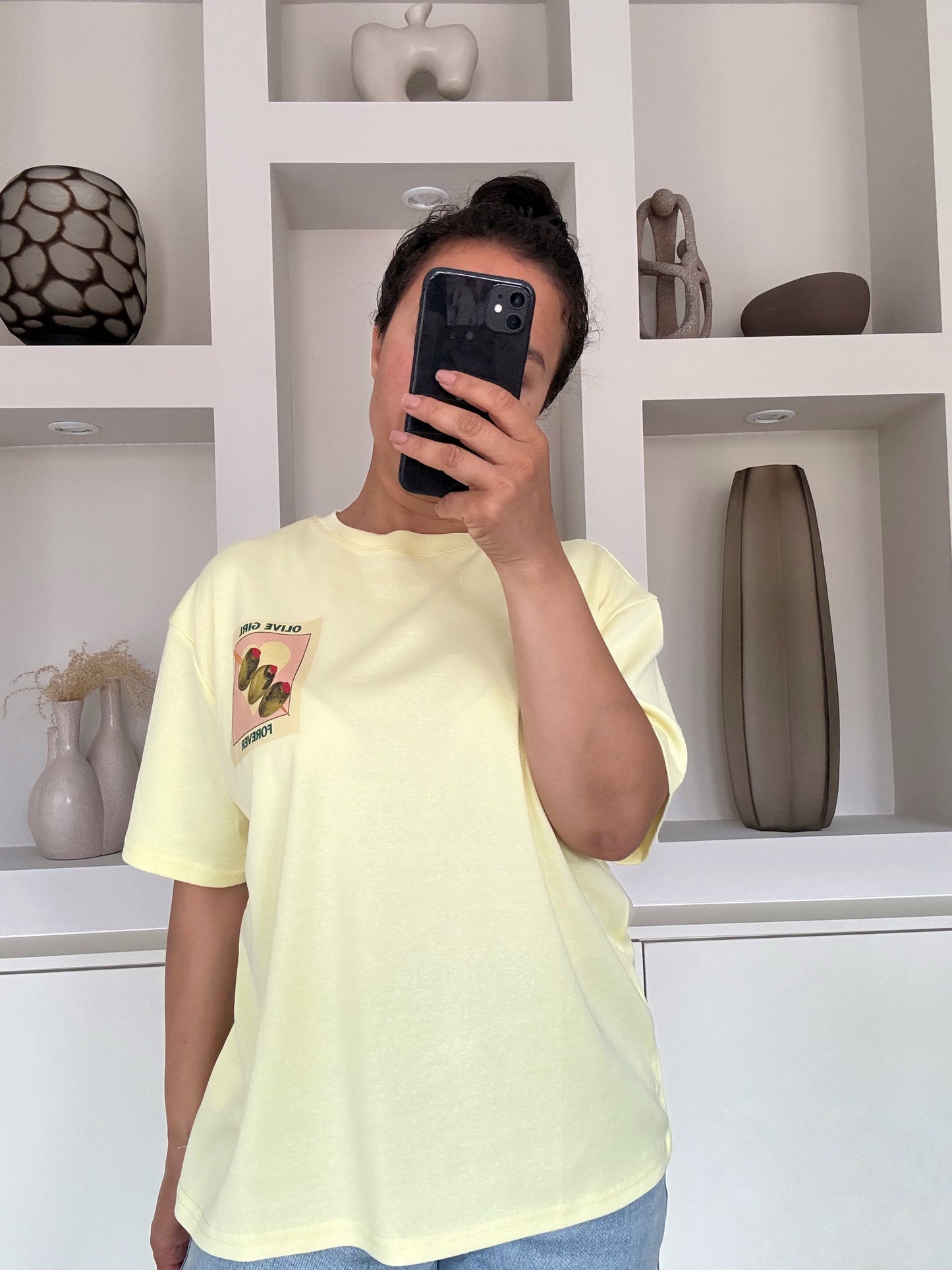 Model draagt The olive girl tee in pastelgele kleur met illustratie en tekst op de borst – VYNAH