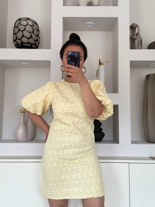 Model draagt de Yasmin Puff Dress in pastelgele bloemenprint met pofmouwen – VYNAH