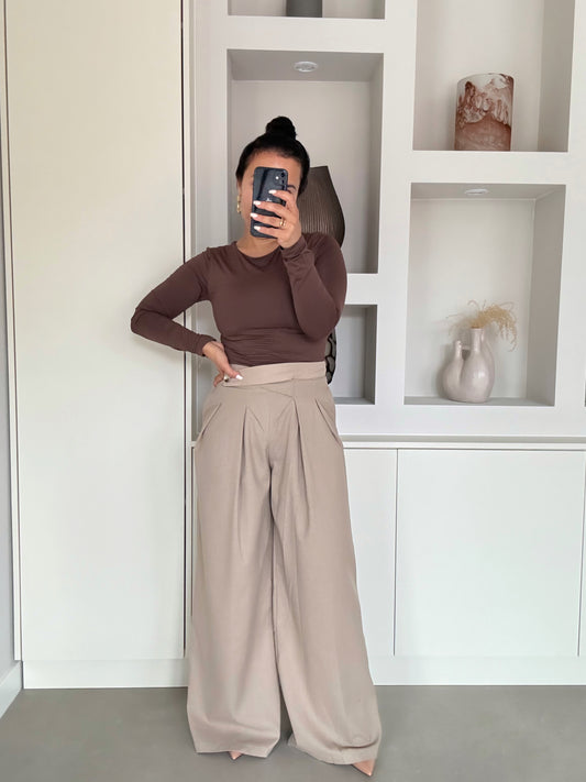 Beige wide leg pantalon met hoge taille en plooien, gecombineerd met een bruine body, close-up